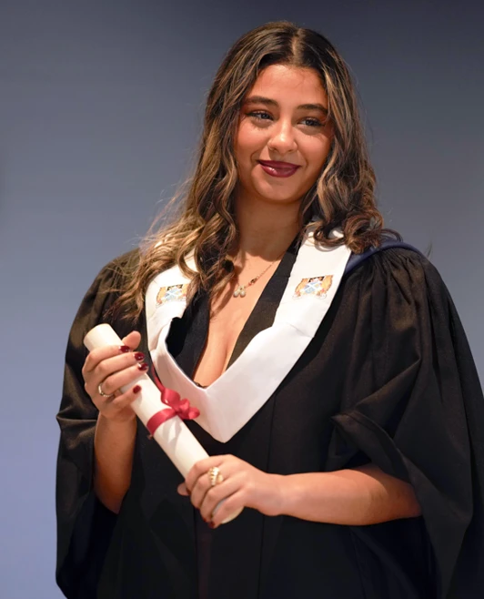 Graduate in gown holding diploma scroll on stage at Glasgow Kelvin College’s 2025 graduation ceremony. Graduate in gown holding diploma scroll on stage at Glasgow Kelvin College’s 2025 graduation ceremony.